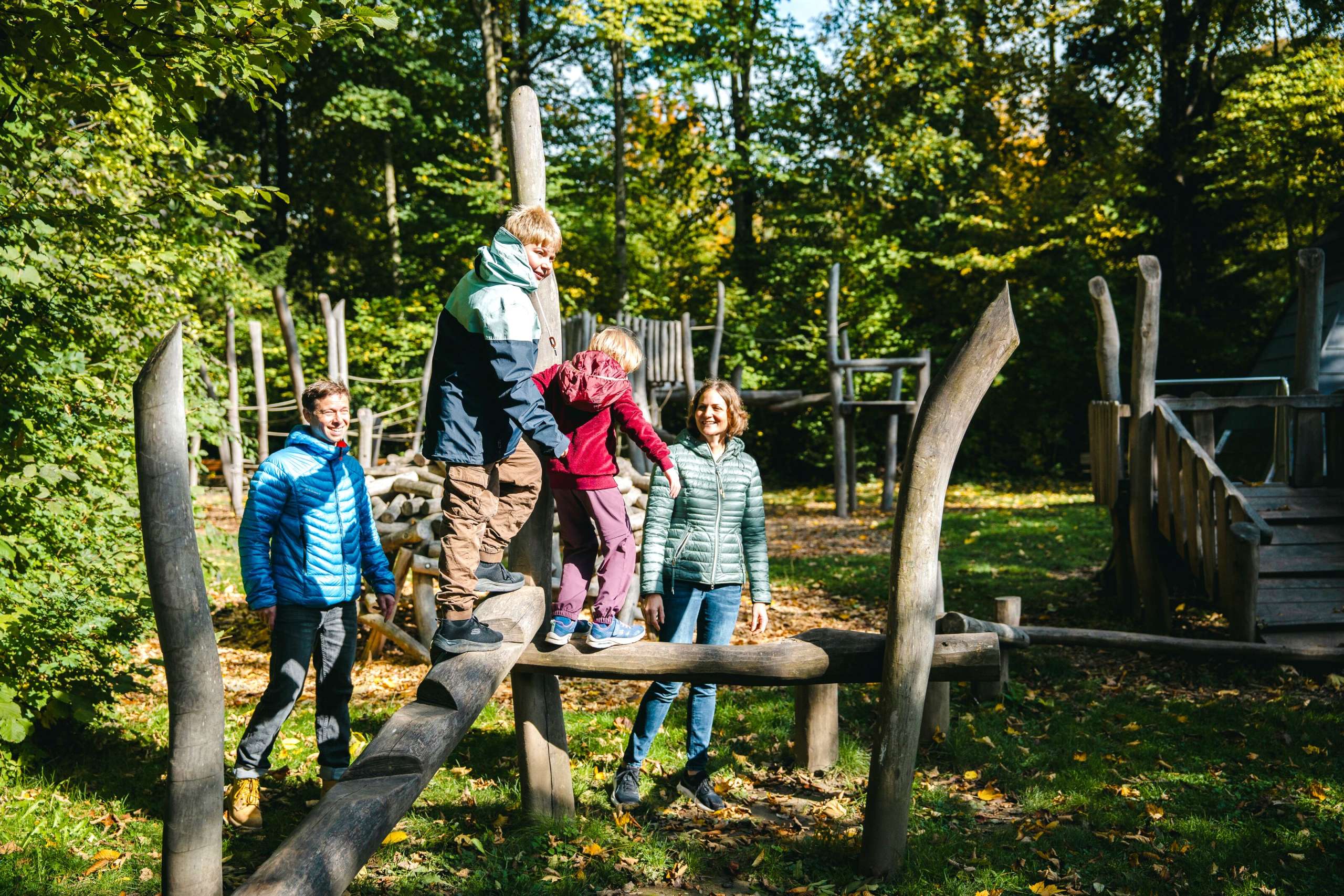 Familie mit zwei Kindern auf dem Spielplatz in Oberburg beim Fussballplatz an der Emme. Der Junge und das Mädchen balancieren auf einem Klettergerüst aus Holz.
